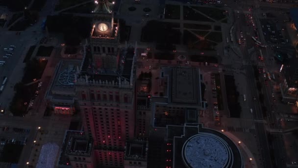 Високий кут огляду Палацу культури і науки з освітленим годинником. Місто вночі. Варшава, Польща — стокове відео