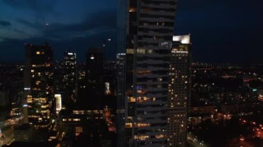 Şehir merkezindeki modern fütüristik ofis veya apartman kulesinin yükselen görüntüleri. Şehir merkezinin gece manzarası. Varşova, Polonya