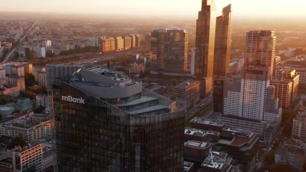 Diavetítés és serpenyő felvétel a modern, magas kereskedelmi épület tetejéről fényes üveghomlokzattal. A belvárosban a fényes reggeli nap ellen. Varsó, Lengyelország — Stock videók