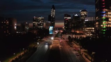 Şehir caddesi şehir merkezindeki gökdelenlere doğru gidiyor. Renkli gökyüzüne karşı modern gökdelenlerin siluetleri. Varşova, Polonya