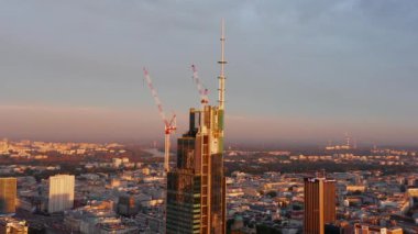 Gökdelen şantiyesinin tepesinin yörüngesinde sabah güneşiyle ışıldayan vinçlerle. Varşova, Polonya