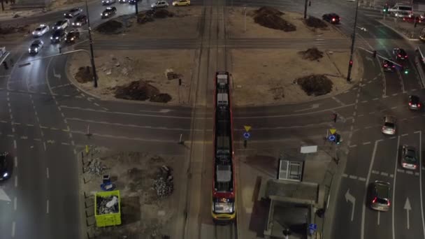 Suivi en avant du tramway traversant un grand rond-point. Inclinez-vous révéler de la circulation en soirée sur la route à voies multiples dans la ville. Varsovie, Pologne — Video