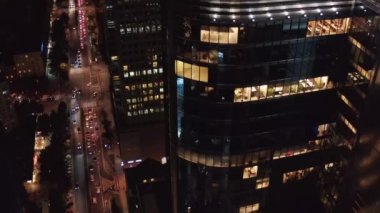 Işıkları yansıtan parlak yüzlü modern yüksek katlı ofis binası. Uzun, işlek caddeyi ortaya çıkarmak için yukarı doğru eğil. Varşova, Polonya