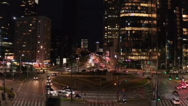 Передній політ над жвавою вулицею і багатосмуговим кругом в нічному місті. Вечір у центрі міста. Варшава, Польща — стокове відео