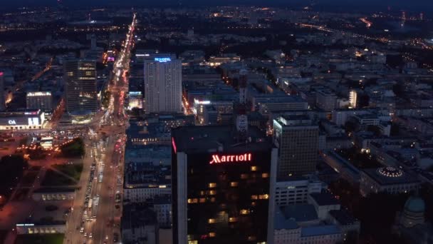 Slide e pan filmagem de arranha-céus do hotel moderno alto e rua movimentada levando ao redor. Tráfego noturno no centro da cidade. Varsóvia, Polónia — Vídeo de Stock