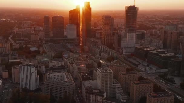 Fly above large city. Tilt up reveal downtown skyscrapers against bright sunset light. Warsaw, Poland — Stock Video