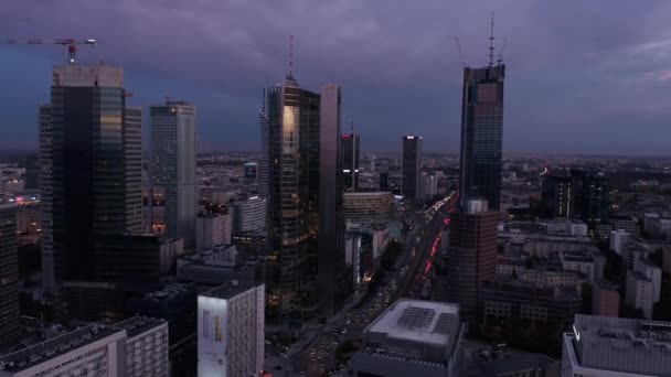 Wieżowce w centrum po zachodzie słońca. Przechylić w dół ujawniając ruchliwe ulice i duże rondo. Warszawa, Polska — Wideo stockowe