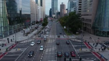 Şehirdeki çok şeritli yolda giden arabanın izini sürüyorum. Uzun modern ofis ya da apartman binaları. Varşova, Polonya