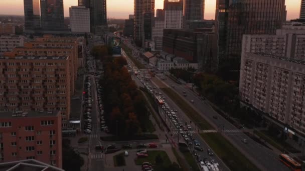 Vola sopra la strada trafficata. Tilt up rivelano di alti grattacieli del centro contro il colorato cielo del tramonto. Varsavia, Polonia — Video Stock