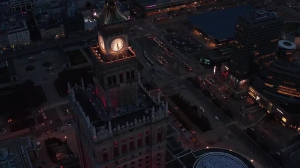 Vysoký úhel pohledu na noční město. Vysoké budovy s věžovými hodinami a provoz v ulicích níže. Varšava, Polsko — Stock video