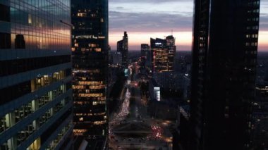 Yoğun çoklu şeritli yoldaki modern yüksek binalar ve büyük döner kavşak pisti arasındaki dar görüş. Alacakaranlık gökyüzü. Varşova, Polonya