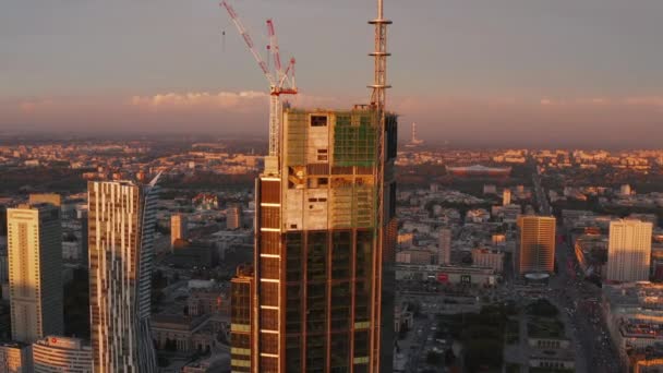 Volare intorno al nuovo moderno cantiere grattacielo con gru in alto fuori terra. L'ora d'oro della sera. Varsavia, Polonia — Video Stock
