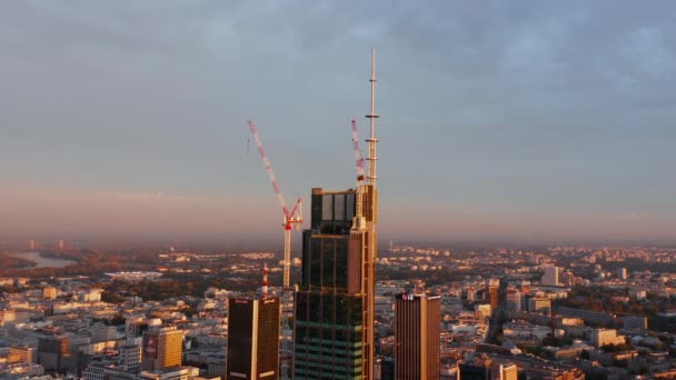 Будівництво нового сучасного висотного підйому будівлі центру міста. Вежі-журавлі на місці. Сцена освітлена ранковим сонцем. Варшава, Польща — стокове відео