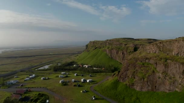 Краєвид на дивовижну зелену місцевість Ісландії. Дрони повітряного огляду, що літають над приголомшливим краєвидом з караваном і туристичним мандрівником-кемпером. Дивовижне місце для подорожей по природі — стокове відео