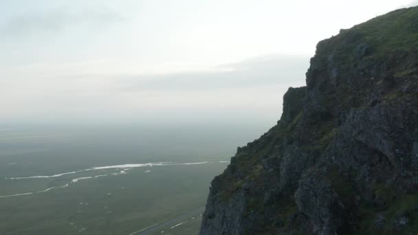 アイスランドの田舎で岩だらけの苔むした崖の鳥の目のドローンビュー。南アイスランドの気分の良い高地を明らかにする空中ビュー。霧の風景 — ストック動画