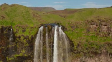 İzlanda 'daki Seljalandsfoss şelalesinin havadan görünüşü. Yüksek uçurumlardan akan suyun destansı drone görüntüsü. Doğada şaşırtıcı ve güzel