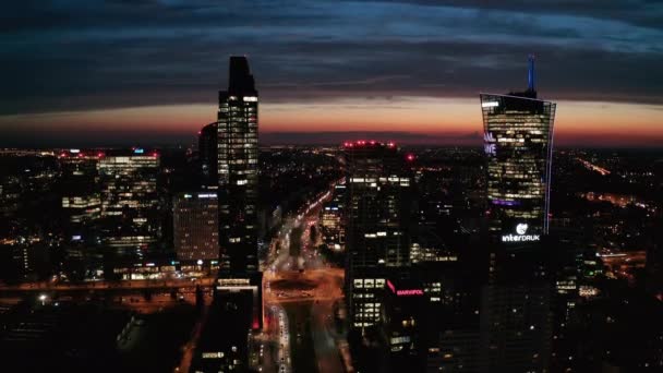 Imágenes descendentes panorámicas aéreas de rascacielos modernos contra el colorido cielo al atardecer. Silueta de edificios de gran altura con ventanas iluminadas. Varsovia, Polonia — Vídeo de stock