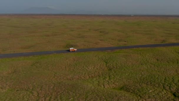 Drone vista deslizante carro viajando pacificamente em Ring Road, na Islândia. Vista aérea carro de condução turística descobrindo a natureza selvagem na Islândia com paisagem panorama idílico — Vídeo de Stock