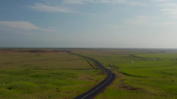 アイスランドで最も重要な高速道路である環状道路を航空路で走るビューカー。花の田舎の荒野で車で旅行冒険的な観光客のドローンの視点 — ストック動画