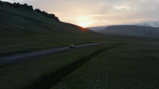 Birds eye view car peacefully driving on ring road, the most important highway in Iceland. Aerial view car driving along empty country road at golden sunset — Stock Video