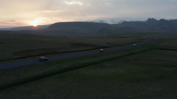 Luchtfoto drone vlucht over avondring wegverkeer in IJsland. Vogels oog van auto 's rijden langs rechte weg door grasrijke hooglanden vallei bij zonsondergang — Stockvideo