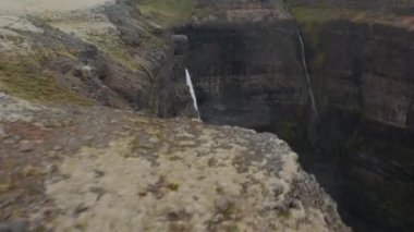 İzlanda 'daki Haifoss ve Granni şelalesinin havadan görünüşü. İki su püskürtüsünün kayalara çarpıp su tozuna dönüştüğünü gösteren drone görüntüsü. Fossa nehrinde şelale