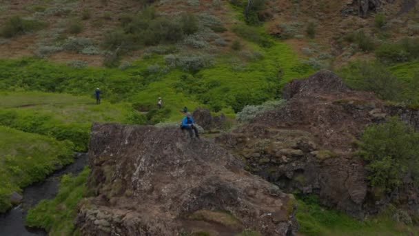 Drone view man sitter bergstopp på Island tittar på fantastiska panorama känsla gratis. Flygfoto turist man vandrare på toppen av klippformation meditera titta på fantastiska islandskap — Stockvideo