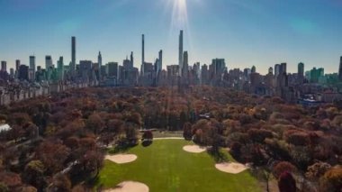 Güneşli bir günde sonbahar ağaçlarıyla Central Park 'ın üzerinde ilerliyorlar. Arka planda şehir merkezi gökdelenleri olan geniş bir hiperhız. Manhattan, New York City, ABD