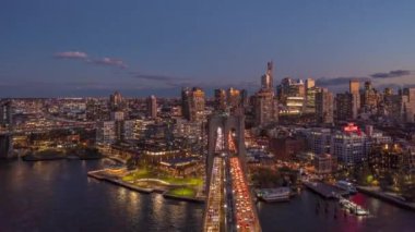 Brooklyn köprüsünün üzerinde alacakaranlıkta ilerliyorlar. Yollardaki yoğun trafiğin alacakaranlıkta süratle düşmesi ve binalardaki ışıklı pencereler. Brooklyn, New York City, ABD