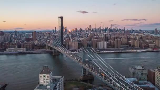 Adelante vuelan sobre el puente de Manhattan. Mucho tráfico en las carreteras y en el agua. Skyline con rascacielos del centro contra el cielo rosado crepuscular. Manhattan, Nueva York, Estados Unidos — Vídeos de Stock