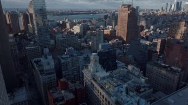 Şehirdeki binaların üzerinden ileriye doğru uçuyor. Nehir ve şehir merkezindeki gökdelenleri gösteren manzarayı kaldır. Manhattan, New York City, ABD