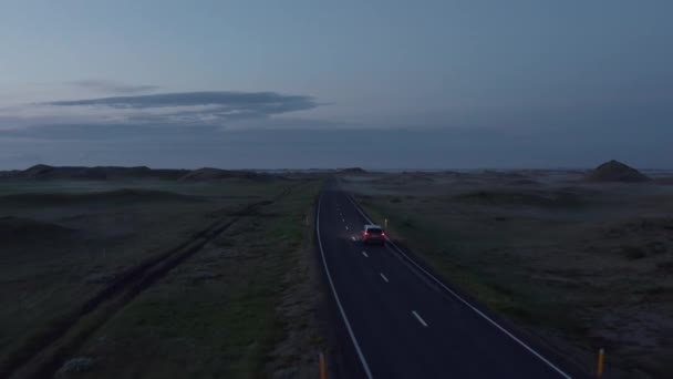 Luchtfoto van de ringweg in IJsland met snelrijdende auto bij zonsondergang. Top uitzicht vanaf drone van de snelweg auto rustig rijden bij zonsondergang — Stockvideo