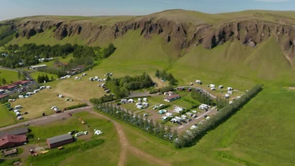 Flygfoto över gröna Island landsbygd med campingplats för turister. Drönare utsikt över liten by på grön äng av isländska höglandet — Stockvideo