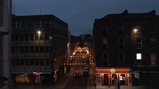 En avant voler au-dessus de la rue étroite éclairée dans le centre-ville. Chaînes lumineuses décoratives à travers l'allée. Scène nocturne. Limerick, Irlande — Video