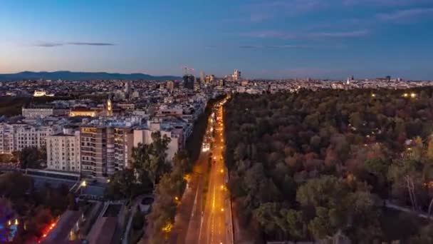 A frente voa acima da cidade grande no crepúsculo. Estrada multipista movimentada que leva ao longo do Parque El Retiro. Imagens de hiperlapso com céu gradualmente escurecendo. Madrid, Espanha — Vídeo de Stock