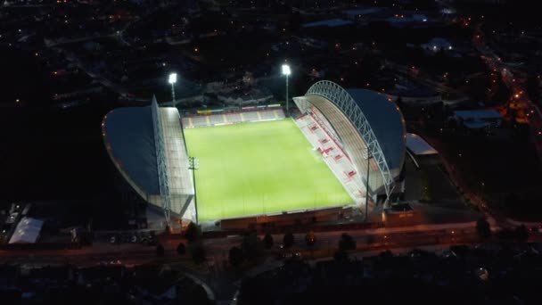 Vista aérea del estadio de fútbol brillando en la noche. Luces brillantes que iluminan el patio verde. Limerick, Irlanda — Vídeo de stock