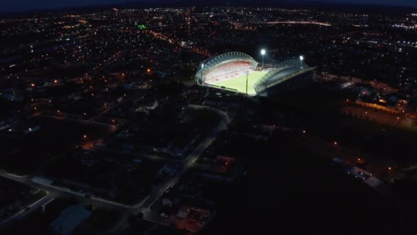 Imágenes panorámicas descendentes de la ciudad nocturna con un brillante estadio de fútbol iluminado. Limerick, Irlanda — Vídeo de stock