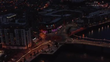 Nehir kıyısındaki kavşaktan geçen arabaların hava görüntüsü. Gece şehrinde trafik az. Limerick, İrlanda