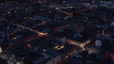 Geceleri şehirli mahallelerin üzerinden uç. Işıklarla aydınlatılan binaların ve sokakların havadan görünüşü. Limerick, İrlanda