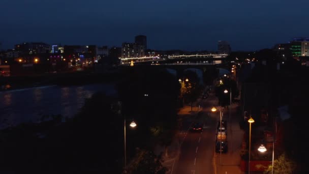 Nehir kenarındaki Shannon caddesinin üzerinde uçuyorlar. Köprü ve diğer kıyıda aydınlatılmış rıhtım. Limerick, İrlanda — Stok video