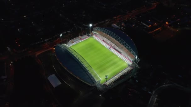 Vista de alto ângulo do estádio de futebol vazio iluminado. Incline-se revelar cena da cidade noite. Limerick, Irlanda — Vídeo de Stock