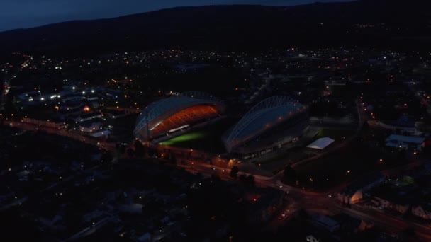 Deslize e pan filmagem de show de luz e ligar as luzes principais no estádio de futebol. Fotografia aérea do centro desportivo na cidade à noite. Limerick, Irlanda — Vídeo de Stock