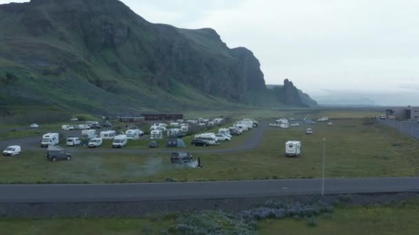 Aerial view motorhomes parked in background mossy mountain nature landscape in Iceland. Drone view motorhomes camping campsite in grassy highlands in southern Iceland — Stock Video