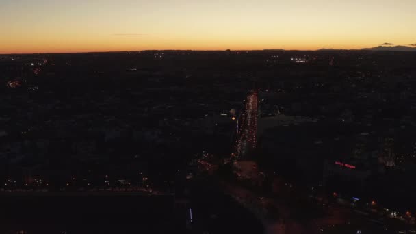 Filmagem panorâmica aérea do tráfego nas ruas da cidade. Cena escura contrastando com céu brilhante por do sol. — Vídeo de Stock