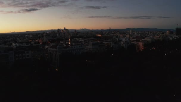 Gün batımından sonra şehrin iniş görüntüleri. Renkli alacakaranlık gökyüzüne karşı binaların ve ağaçların siluetleri. — Stok video