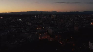 Akşam şehrinin üzerinden uç. Renkli alacakaranlık gökyüzü altındaki sönük kasabanın panoramik hava manzarası.