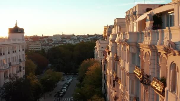 Vorwärts fliegen über breite Straße und entlang schöne dekorative Fassade des historischen mehrstöckigen Palastes beleuchtet von hellem Sonnenuntergang Licht. — Stockvideo