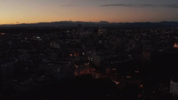 Vuela por encima de la ciudad nocturna. Vista aérea panorámica de la ciudad atenuada bajo el colorido cielo crepuscular. — Vídeos de Stock