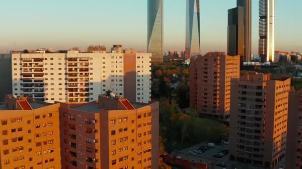 정원은 저녁 햇살이 비추는 주택 단지의 색 아파트 건물 위를 날아 다닙니다. 뒤에 보이는 현대 의고 층 사무실 건물. — 비디오