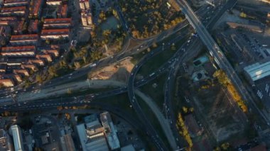 Şehirdeki yoğun çoklu şeritli otoyol kavşağının yüksek açılı görüntüsü. Kalabalık saatlerde anayolda yoğun bir trafik var. Akşam altın saati.